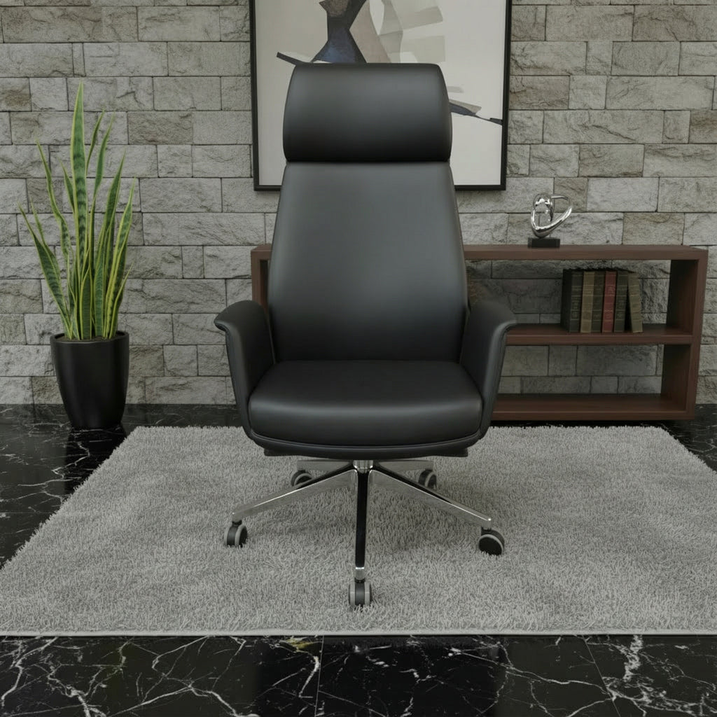 Black leather executive office chair with chrome wheels displayed front side on a grey rug in a modern stone-wall office — high end ergonomic seating by DreamSpace Collection Ontario.